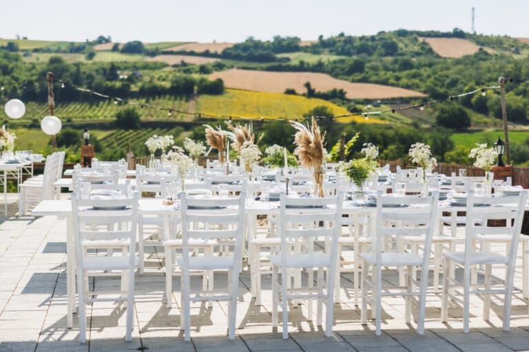 Ricevimento di matrimonio all’aperto con tavoli bianchi allestiti in una location immersa nella campagna