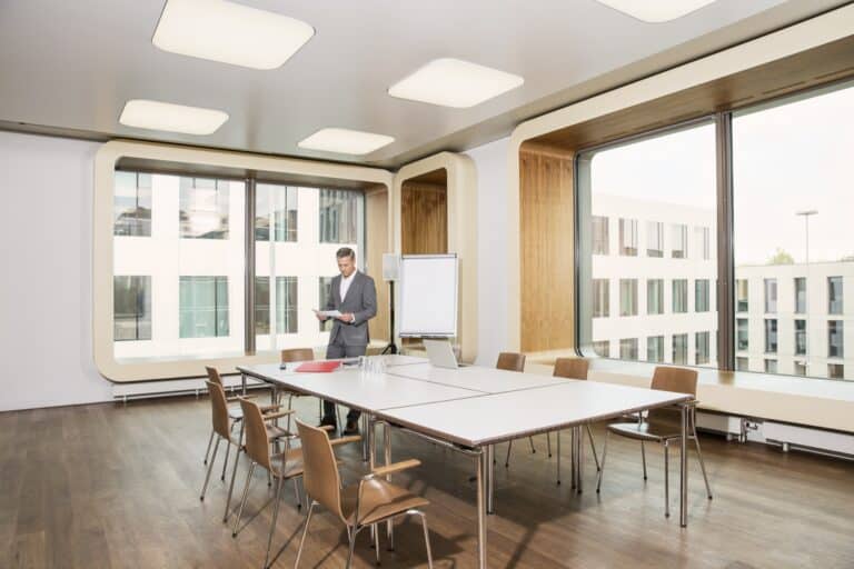 Sala workshop moderna con tavoli modulari, lavagna e ampie finestre