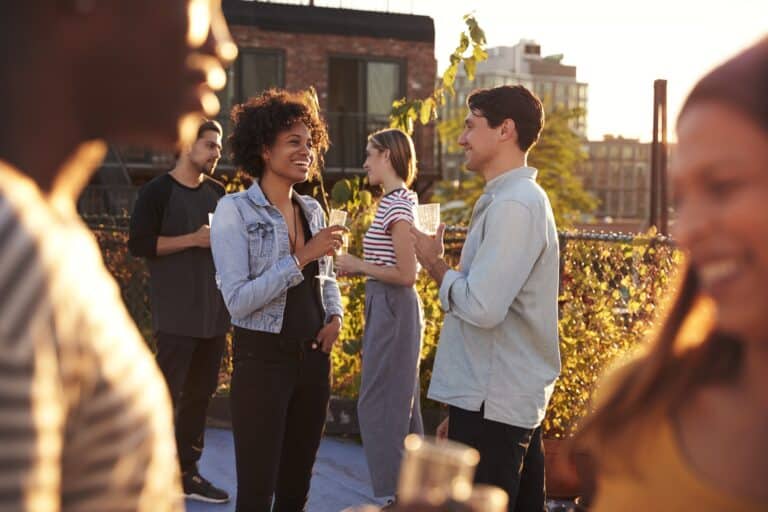 Persone che conversano durante un evento aziendale su rooftop al tramonto