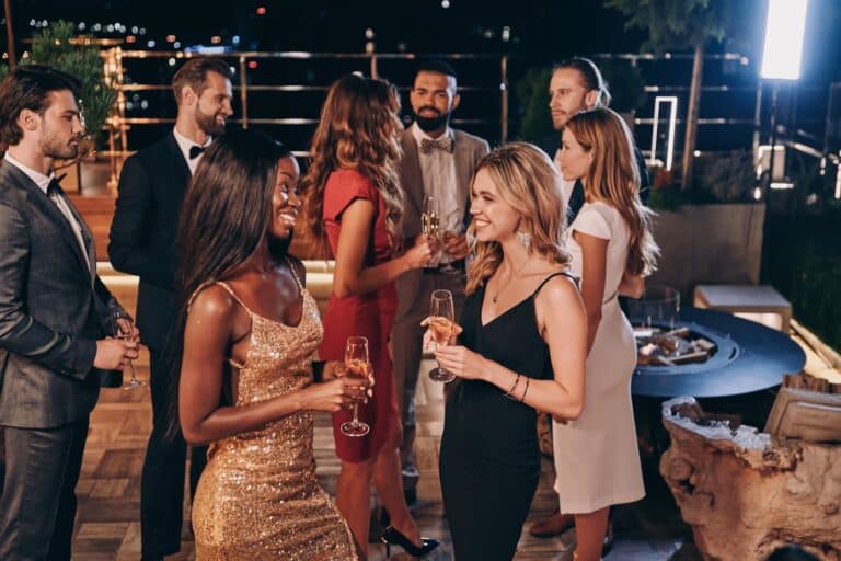 Persone eleganti durante un evento estivo serale in una venue outdoor con terrazza