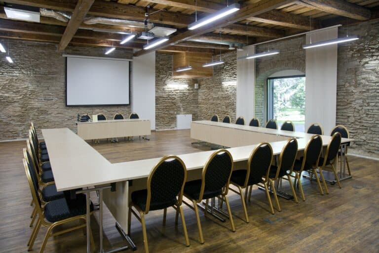 Sala riunioni con tavoli disposti a U, sedie e schermo per meeting aziendale