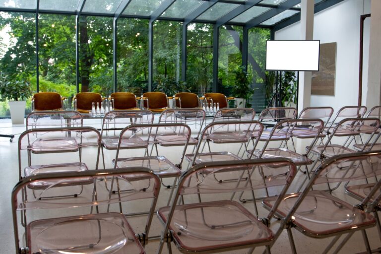 Sala conferenze con sedute, tavolo relatori e schermo per presentazioni aziendali