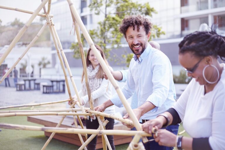 Colleghi collaborano alla costruzione di una struttura durante un team building all’aperto