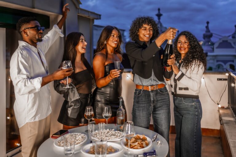 Gruppo di amici brinda durante un cocktail party serale su una terrazza