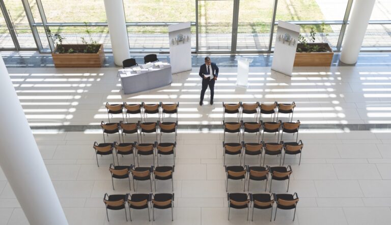 Responsabile prepara una sala per un evento aziendale con palco e sedute
